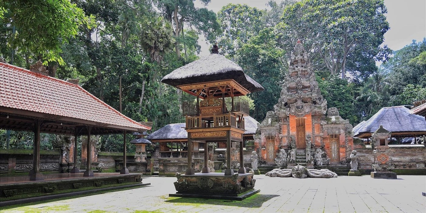 Ancient stone temple surrounded by mossy relief carvings and deep green jungle flora inside the Ubud Monkey Forest